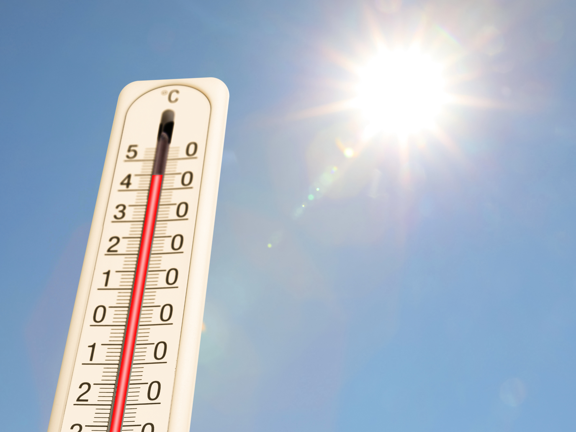 Thermometer rising in direct sunlight during a heatwave, highlighting the impact of extreme heat on business continuity and remote working.