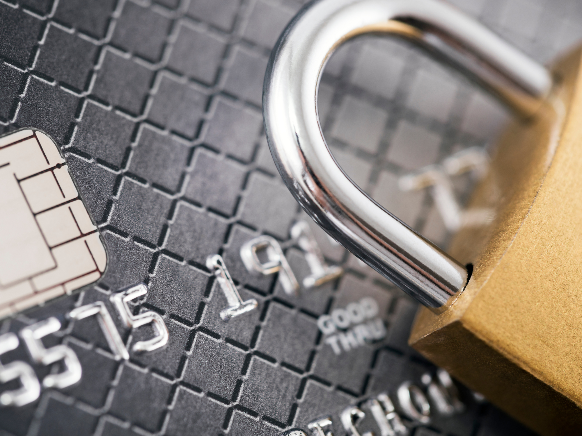 A padlock resting on a credit card, illustrating PCI DSS compliance and payment card security.