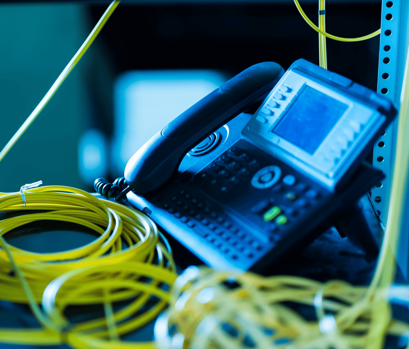 Business IP phone beside fibre network cables representing Mitel and VoIP connectivity