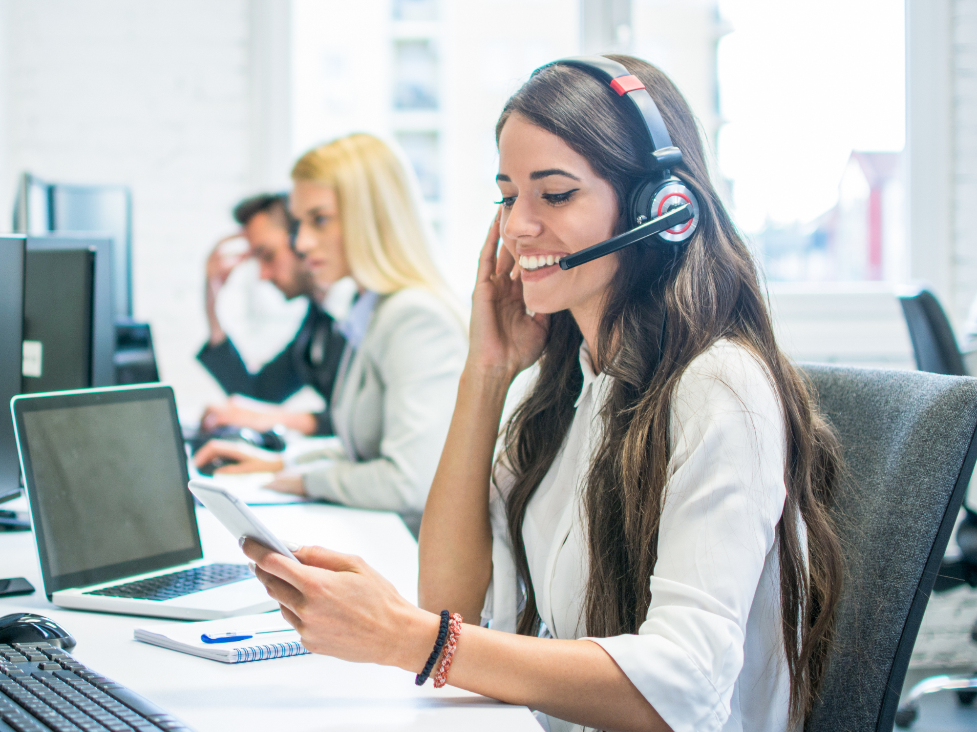 Customer service team member using a headset and mobile phone in an office